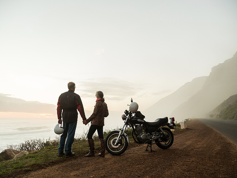 Ein Rentnerpaar auf einer Motorradfahrt an einer Küste
